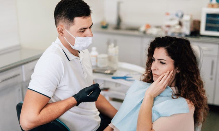 Patient holding jaw in pain, using phone